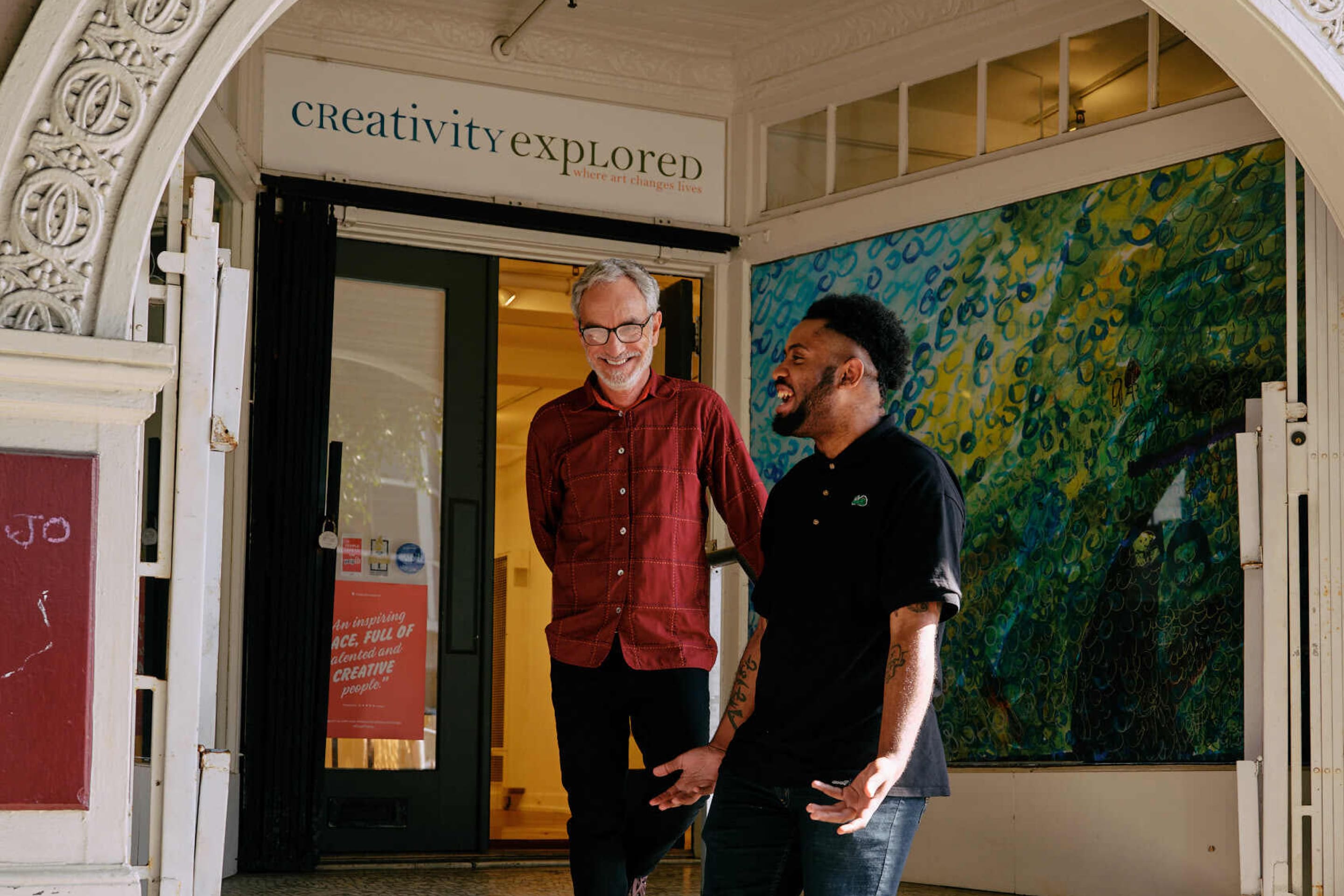 Joseph "JD" Green and Glenn Peckman laugh together outside of Creativity Explored.